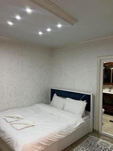 a bedroom with a bed with white sheets and a mirror at Hotel Premium in Pristina