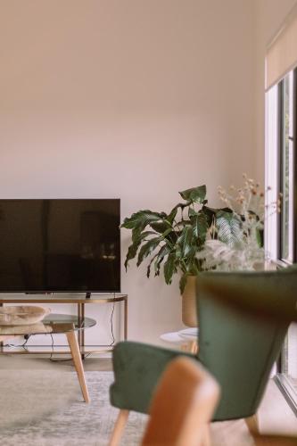 a living room with a tv and some plants at Little Lodge - Willunga - C21 SouthCoast Holidays in Willunga