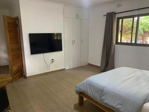 a bedroom with a bed and a flat screen tv at The ranch apartments, en-suite rooms in Lusaka