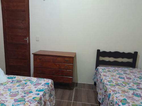 a bedroom with two beds and a wooden dresser at Chalé Primavera in Guaramiranga