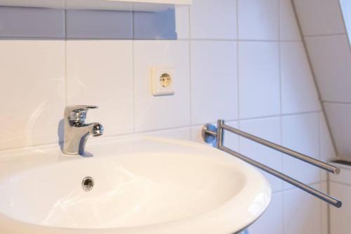 a white sink in a white tiled bathroom at Wohnung mit 3 Bädern & 2 Küchen in Alzey