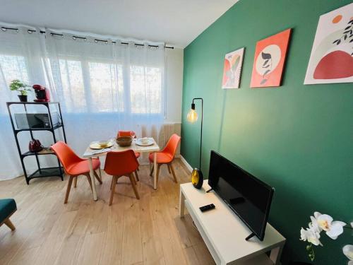 a living room with a table and a tv at Le Vibrant Bubble - Studio Parking 10 min U-Arena La Défense in Houilles