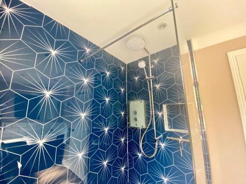a bathroom with a shower with a blue wall at About Time Meva - stylish two-bedroom, dog-friendly home-from-home with parking and garden in Mevagissey