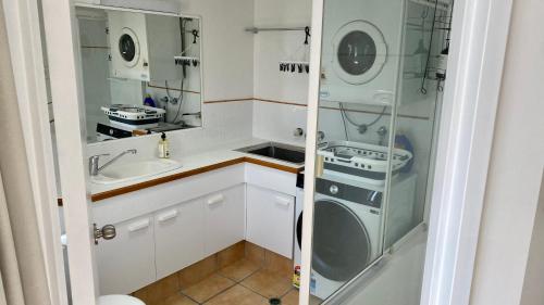 Il comprend une petite cuisine avec un évier et un lave-linge. dans l'établissement Entire 2 Bedroom Apartment w/ Ocean Views, à Coolum Beach