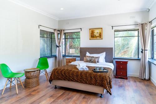 a bedroom with a bed and two green chairs at South Yarra Boutique Maison in Melbourne