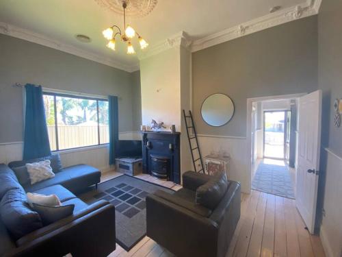 a living room with two couches and a mirror at Charming 3 bedroom wine country cottage in Rutherglen