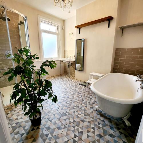 a bathroom with a large tub and a potted plant at Contemporary 3 bed house with spacious garden close to Stratford & Canary Wharf in London