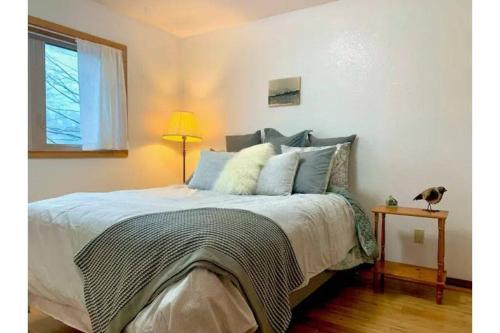 a bedroom with a bed and a lamp and a window at Lovely Condo Across from Downtown w/ Mountain View in Juneau