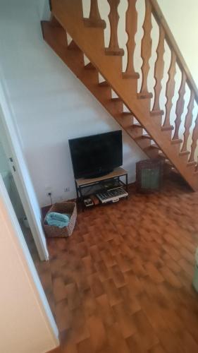 - un salon avec une télévision à écran plat et des escaliers dans l'établissement Les coquelicots., à Mirepoix