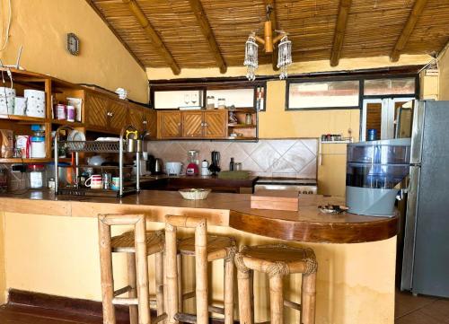 a kitchen with a bar with stools and a refrigerator at Ekilibrium in Los Órganos