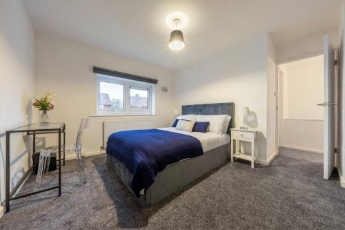 a bedroom with a bed and a table and a window at Modern Wolverhampton 3 bed Home in Wolverhampton