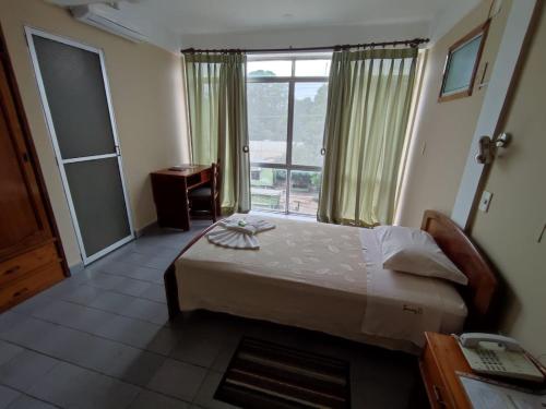ein Schlafzimmer mit einem Bett und einem großen Fenster in der Unterkunft JR HOTEL in Refineria Camiri