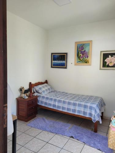 een slaapkamer met een bed en een dressoir en foto's aan de muur bij Pousada da Sissi in Itanhaém