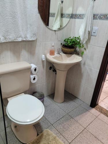 een badkamer met een toilet, een wastafel en een spiegel bij Pousada da Sissi in Itanhaém