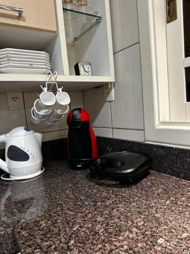 a kitchen counter with a toaster and cups on a shelf at apartamento em bairro nobre suíte com ar condicionado e banheira com hidromassagem in Bento Gonçalves