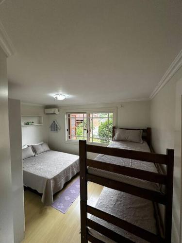 a bedroom with two beds and a window at apartamento em bairro nobre suíte com ar condicionado e banheira com hidromassagem in Bento Gonçalves