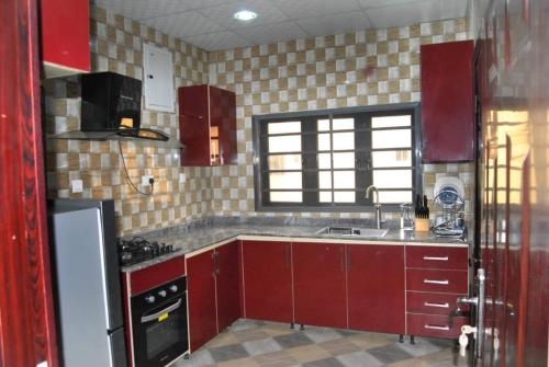 uma cozinha com armários vermelhos e um lavatório em Ibadan Serviced Apartments em Ibadan