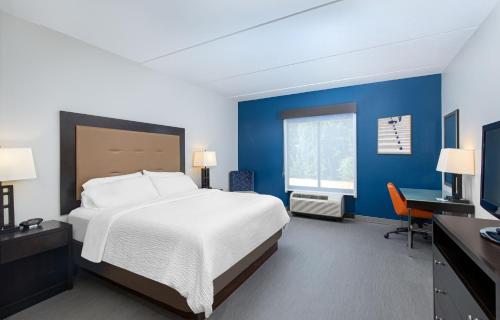 a bedroom with a bed and a desk and a window at Holiday Inn Express & Suites - Cleveland Northwest, an IHG Hotel in Cleveland