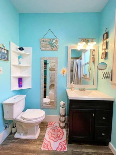 a bathroom with a toilet and a sink and a mirror at The Poolside Bungalow in Galveston