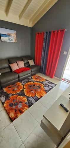 a living room with a couch and a flower rug at Finest Accommodation 75 Blossom, The Orchards innswood St Catherine in Spanish Town