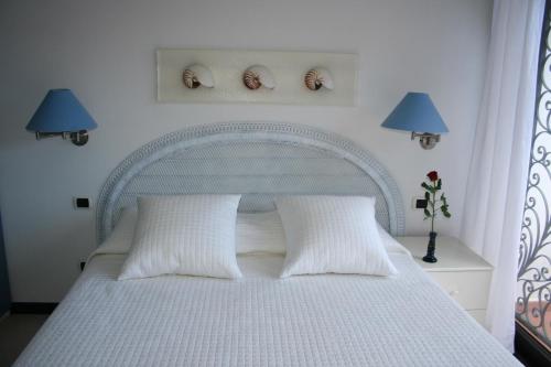ein Schlafzimmer mit einem weißen Bett mit zwei Kissen in der Unterkunft Ferienwohnung in einer privaten Villa mit Meerblickterrasse, auf dem Hügel des Capo Berta in Diano Marina