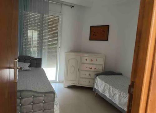een slaapkamer met 2 bedden, een dressoir en een raam bij Duplex El mansoura A1 in Kelibia