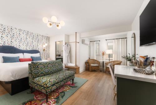 a bedroom with a bed and a chair and a kitchen at Petit Soleil - Bed, Breakfast and Bar in San Luis Obispo