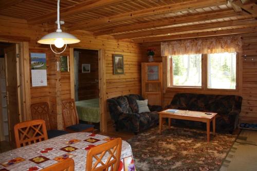 - un salon dans une cabane en rondins avec une table dans l'établissement Ferienhaus in Kouvola mit Terrasse und Grill, à Kouvola