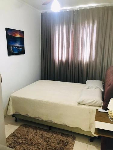 a bedroom with a large bed with a window at Apartamento na Palhoça, com vista para o mar, próximo a mercados, padarias e farmácias. in Palhoça