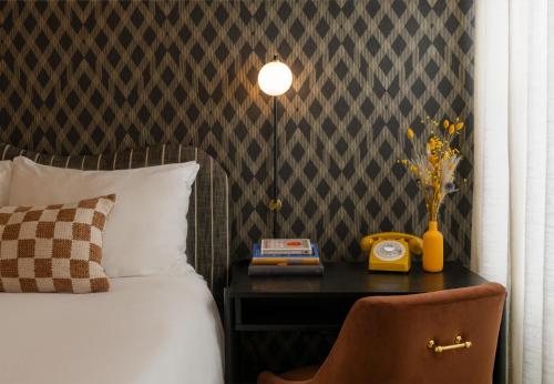 a bedroom with a bed and a table with a phone at Petit Soleil - Bed, Breakfast and Bar in San Luis Obispo