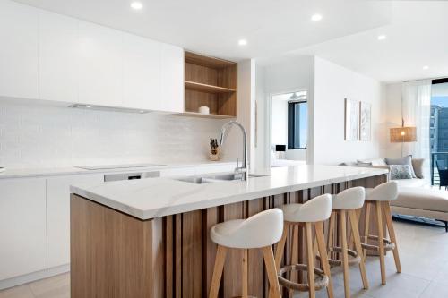 a kitchen with a sink and a counter with stools at 2BR Luxury Central Palm Beach Apartment (Best Location!) in Gold Coast