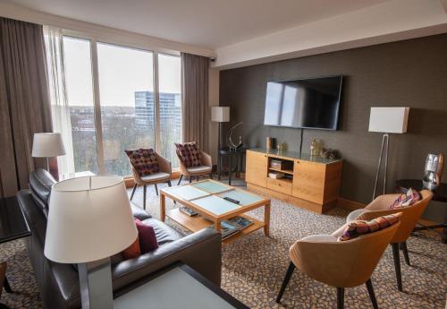 a living room with a couch and chairs and a television at Crowne Plaza Brussels Airport by IHG in Zaventem