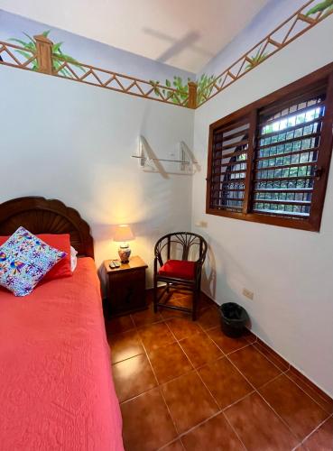 a bedroom with a bed and a chair and a window at Casa Tres Colibries in Mérida