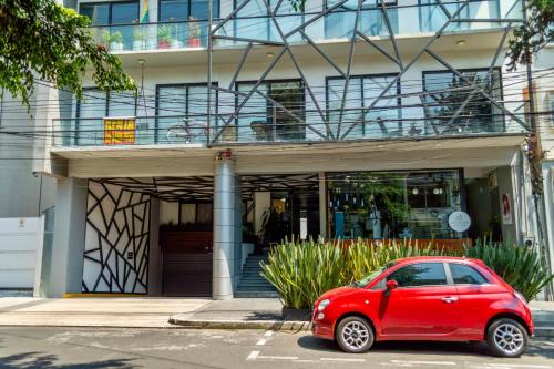une voiture rouge garée devant un bâtiment dans l'établissement Mi Zona Lodging Nápoles, à Mexico