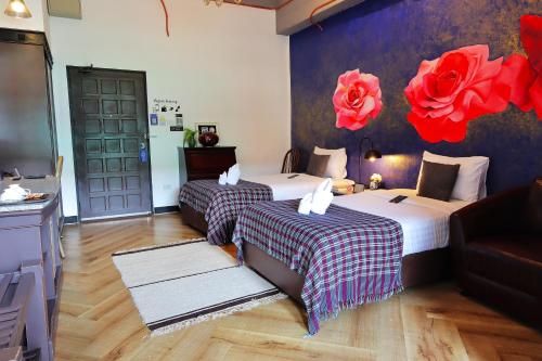 two beds in a room with red flowers on the wall at Yuu Hotel Ubon Ratchathani in Ubon Ratchathani