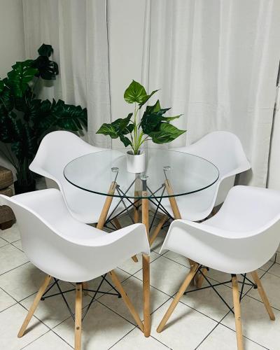 una mesa de cristal con 4 sillas blancas y una maceta en San Juan apartments new en San Juan