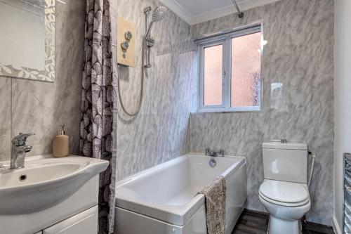 a bathroom with a sink and a toilet and a tub at Large cosy house w/driveway 7pax in Radcliffe
