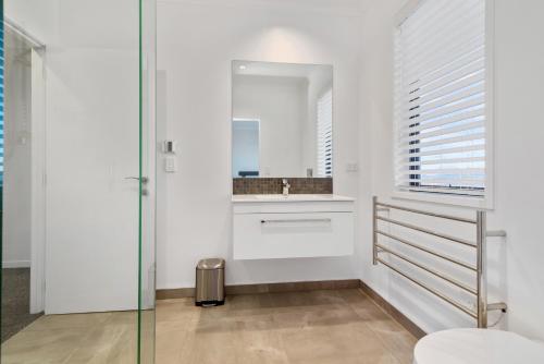 La salle de bains blanche est pourvue d'un lavabo et d'un miroir. dans l'établissement The Lookout, à Rotorua