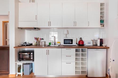 a white kitchen with white cabinets and a microwave at Monte Machial in Alvega