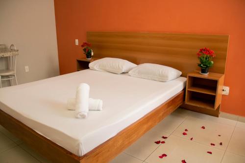 een slaapkamer met een bed met twee handdoeken erop bij Motel Malibu in Divinópolis