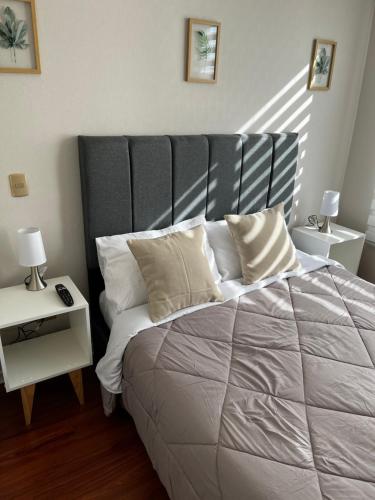 a bedroom with a large bed with white sheets and pillows at Cómodo departamento en el centro de Santiago in Santiago