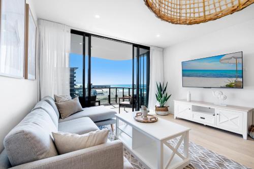 a living room with a couch and a tv at Village Palm Beach - Brand New 2 Bedroom Apartment in Gold Coast