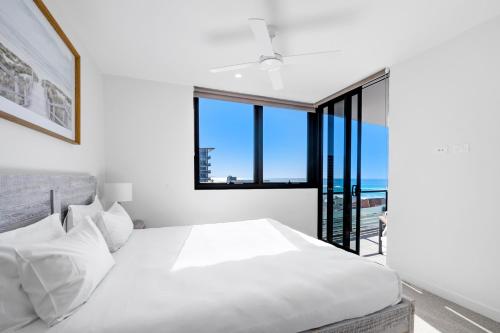 a bedroom with a white bed and a window at Village Palm Beach - Brand New 2 Bedroom Apartment in Gold Coast