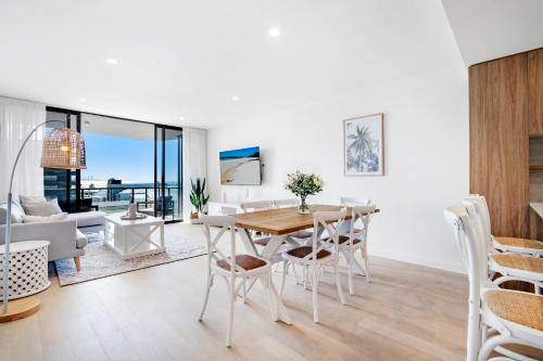 a living room with a wooden table and chairs at Village Palm Beach - Brand New 2 Bedroom Apartment in Gold Coast
