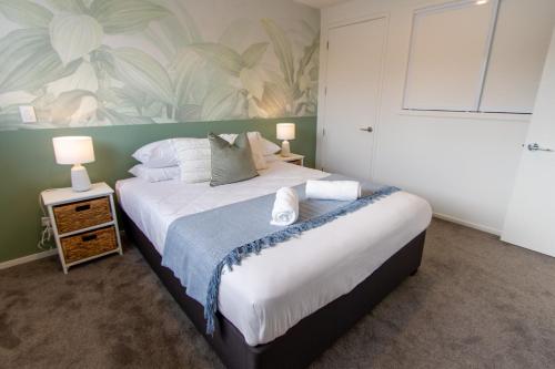 a bedroom with a large white bed with a flower wallpaper at 1 Bedroom Gem with Hagley Park at your doorstep in Christchurch