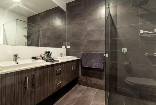 a bathroom with a sink and a glass shower at Luxury home in Christies Beach with King Bed, NBN, Netflix, 3Bed 2Bath in Christies Beach