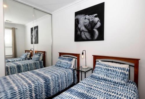 a room with two beds with blue and white stripes at Luxury home in Christies Beach with King Bed, NBN, Netflix, 3Bed 2Bath in Christies Beach