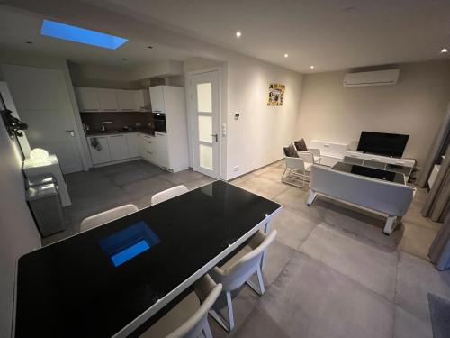 uma sala de estar com uma mesa preta e cadeiras brancas em Apartment Venlose heide em Venlo