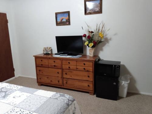 a bedroom with a dresser with a television and flowers on it at Mokee Motel in Bluff