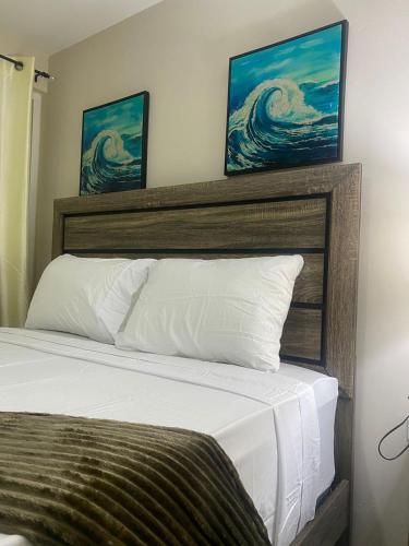 um quarto com uma cama com duas pinturas na parede em Finest Accommodation Bay Front Villa G9 em Portmore